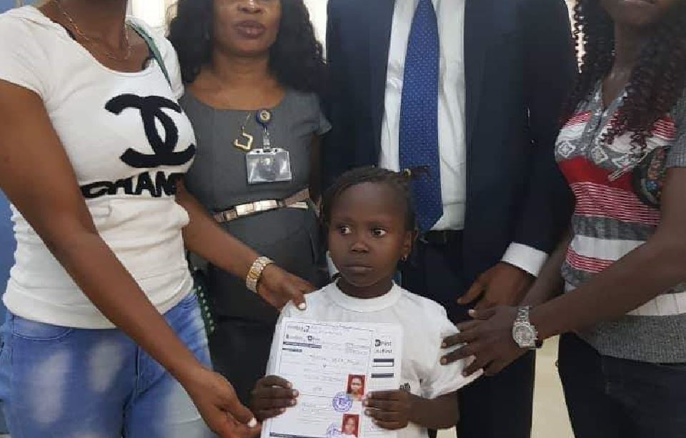 Little Success Adegor displaying her bank account forms with some officials