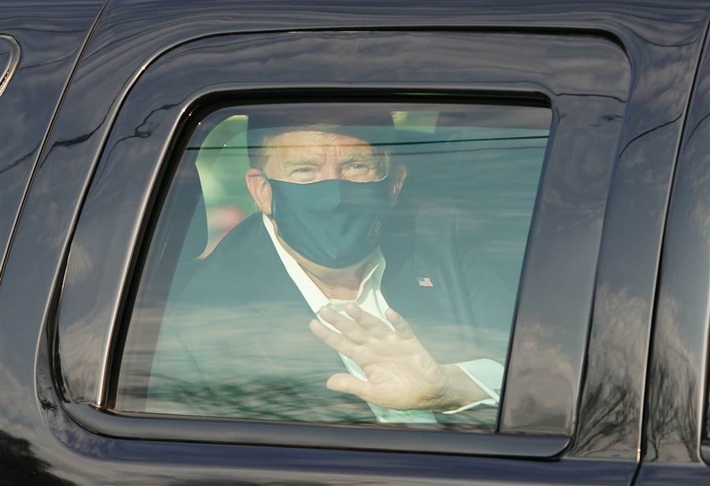 Donald Trump waves to supporters as he rides by in the presidential motorcade in front of Walter Reed National Military Medical Center