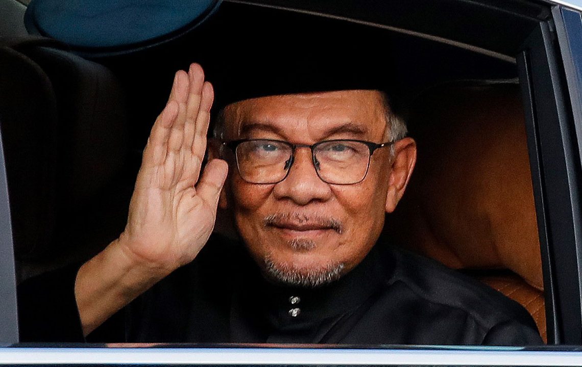 Malaysia's newly appointed Prime Minister Anwar Ibrahim waves from his car as he arrives to take part in the swearing-in ceremony at the National Palace in Kuala Lumpur on November 24, 2022. (Photo by FAZRY ISMAIL / POOL / AFP)